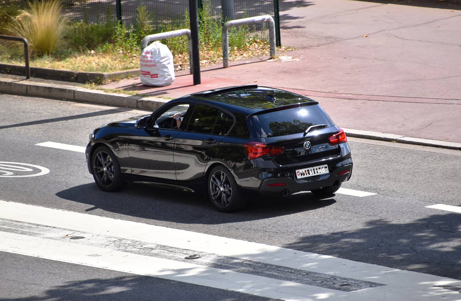 Black BMW M140i, rear three-quarter view