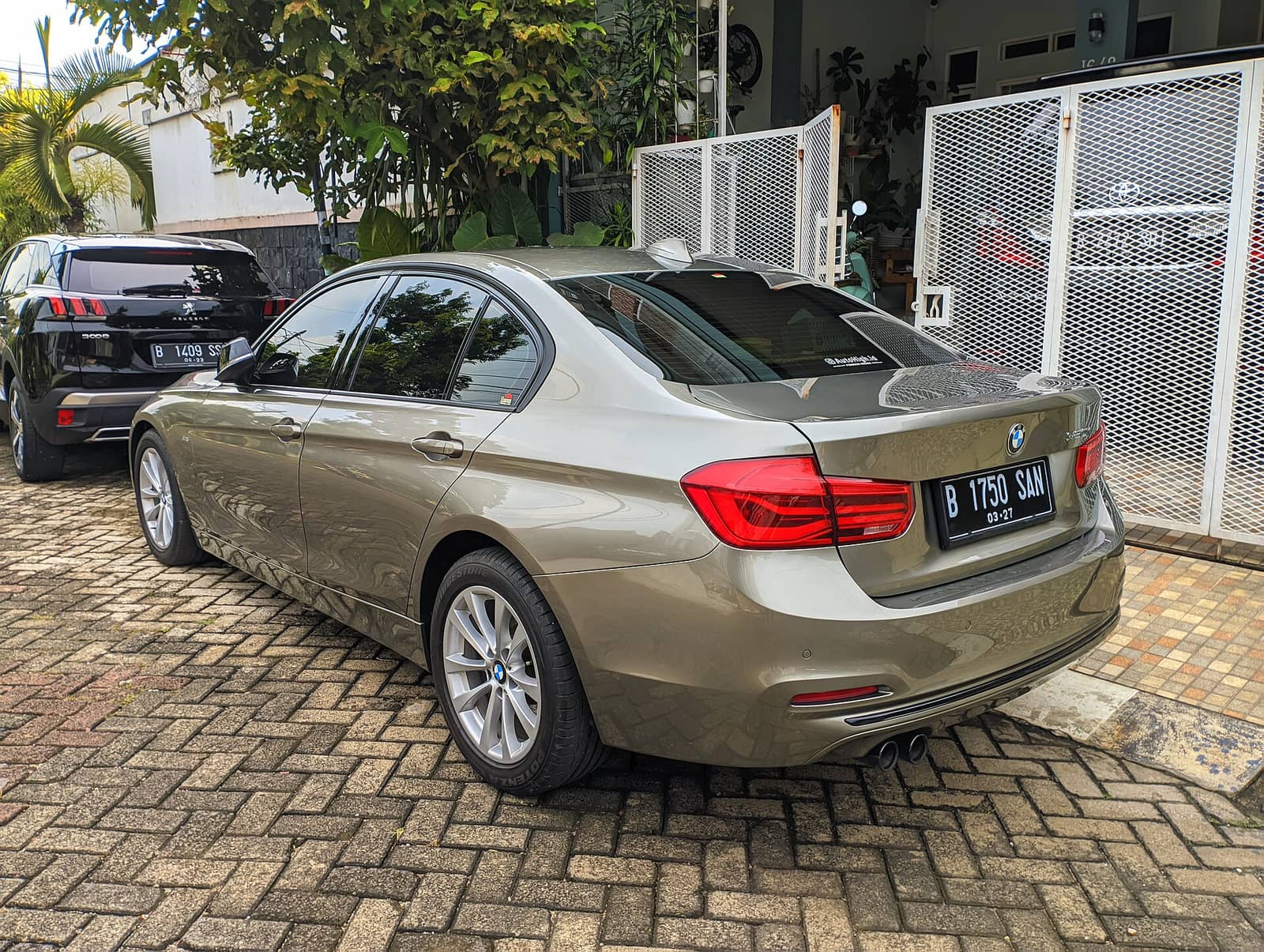 Bronze BMW 320i sedan, rear three-quarter view