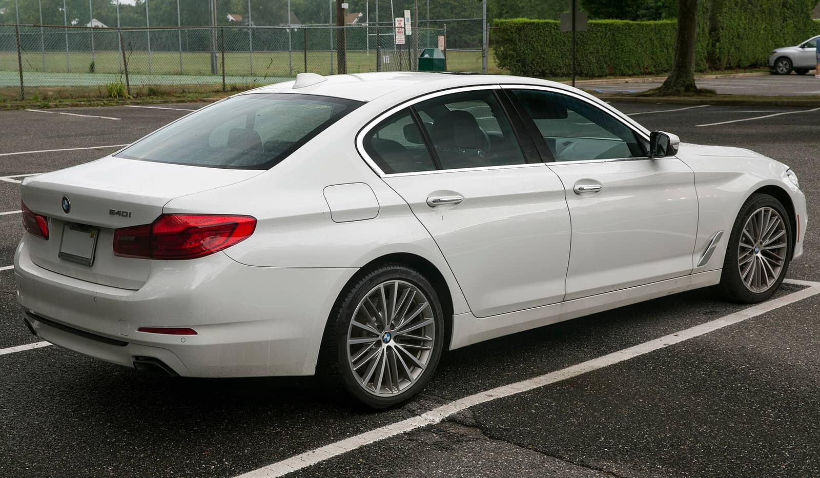 White BMW 5 Series sedan with standard styling, rear three-quarter view