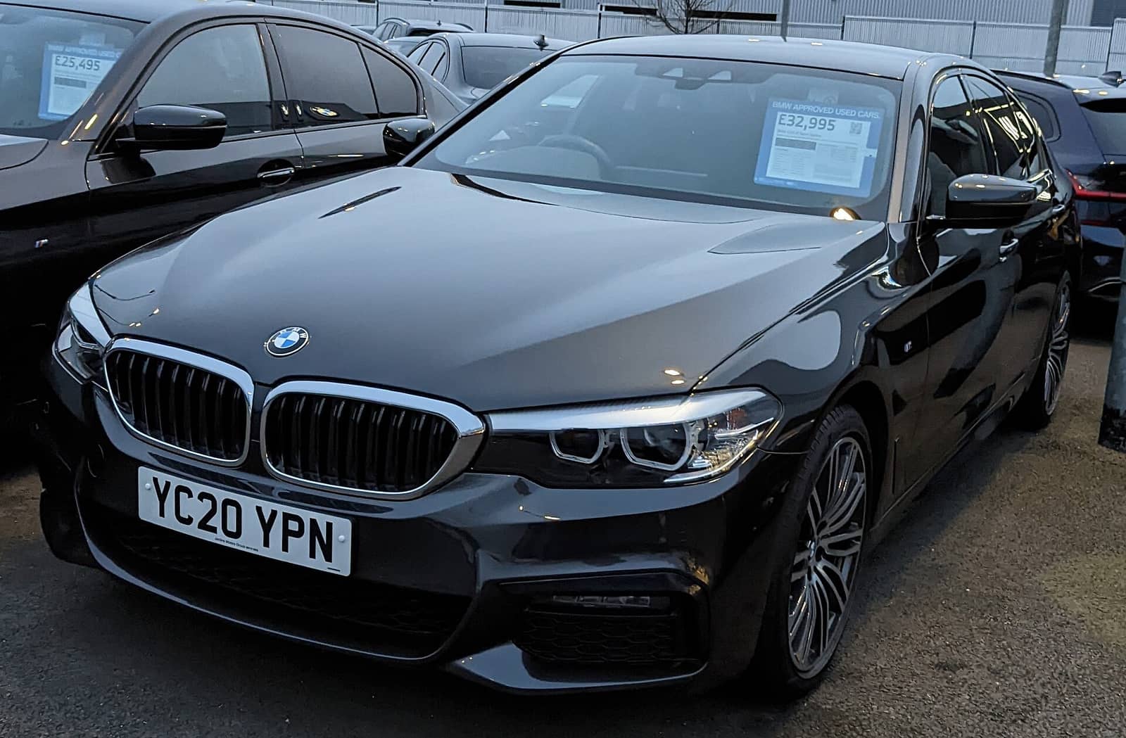 Black BMW 5 Series sedan with standard bumper, front view